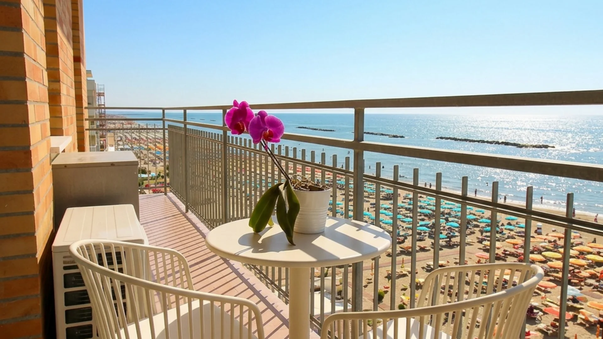 Balcone con tavolo, sedie e orchidea con vista sulla spiaggia e il mare