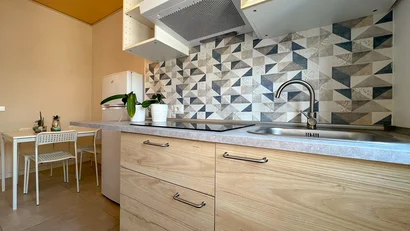 Cucina moderna con piastrelle geometriche, lavello, frigorifero e tavolo da pranzo