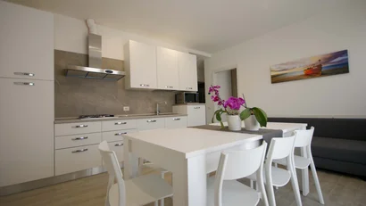 Cucina moderna bianca con tavolo, sedie e orchidee viola