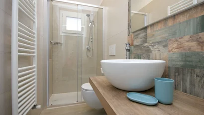 Bagno moderno con lavabo tondo, doccia a vetri e piastrelle colorate