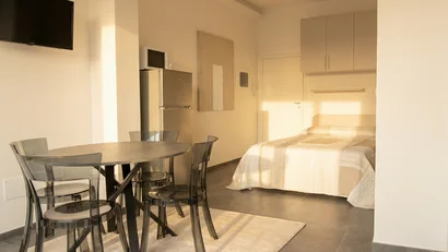 Monolocale moderno con tavolo, sedie trasparenti e letto matrimoniale