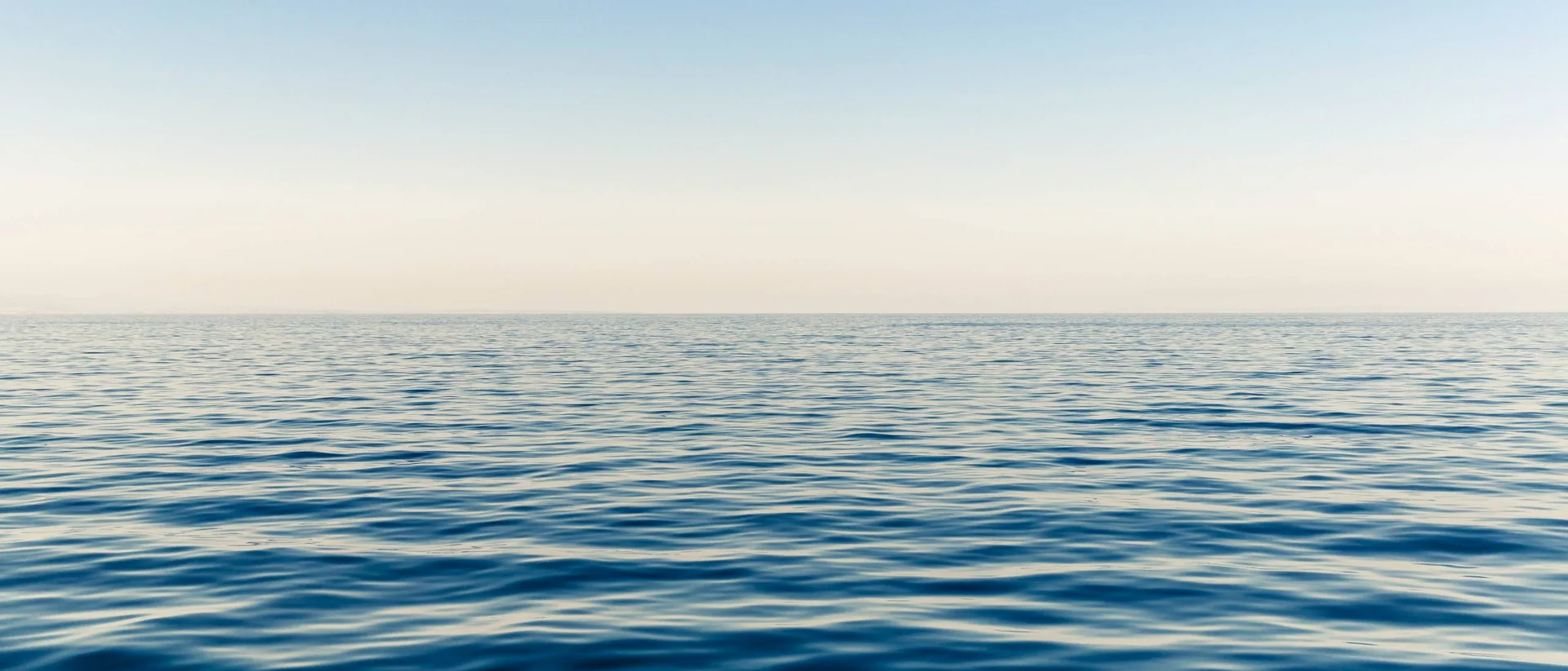 Morbide onde dell'oceano sotto un cielo limpido al tramonto