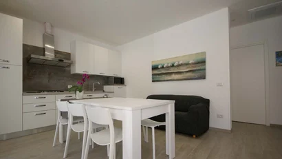 Cucina moderna con tavolo bianco, quattro sedie e divano nero