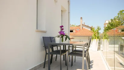 Balcone con tavolo, sedie nere e pianta fucsia in vaso bianco