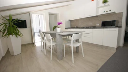 Cucina moderna bianca con tavolo e sedie bianche, pianta e microonde