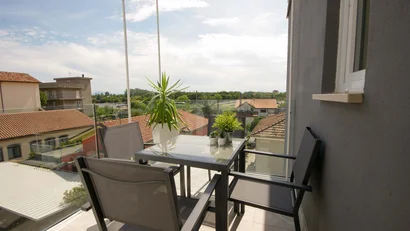 Balcone con tavolo, quattro sedie e piante con vista sul quartiere residenziale